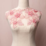 An openwork embroidered dusty pink applique pair in a floral design with swirling stems, 3D flowers and crosshatched leaves displayed on a mannequin.