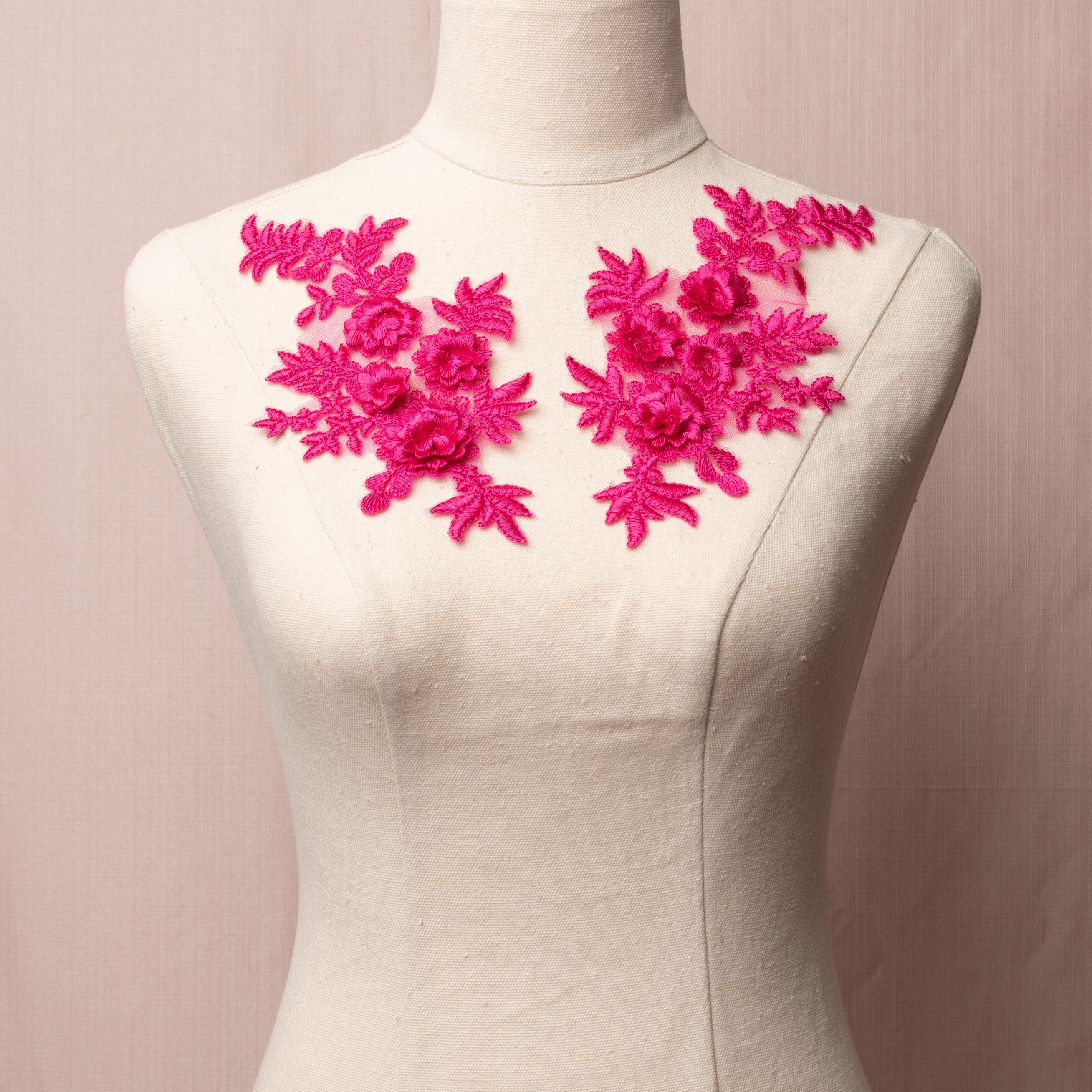Embroidered fuchsia coloured applique pair with a floral design.  The appliques have 3D flowers and are  displayed on a mannequin.