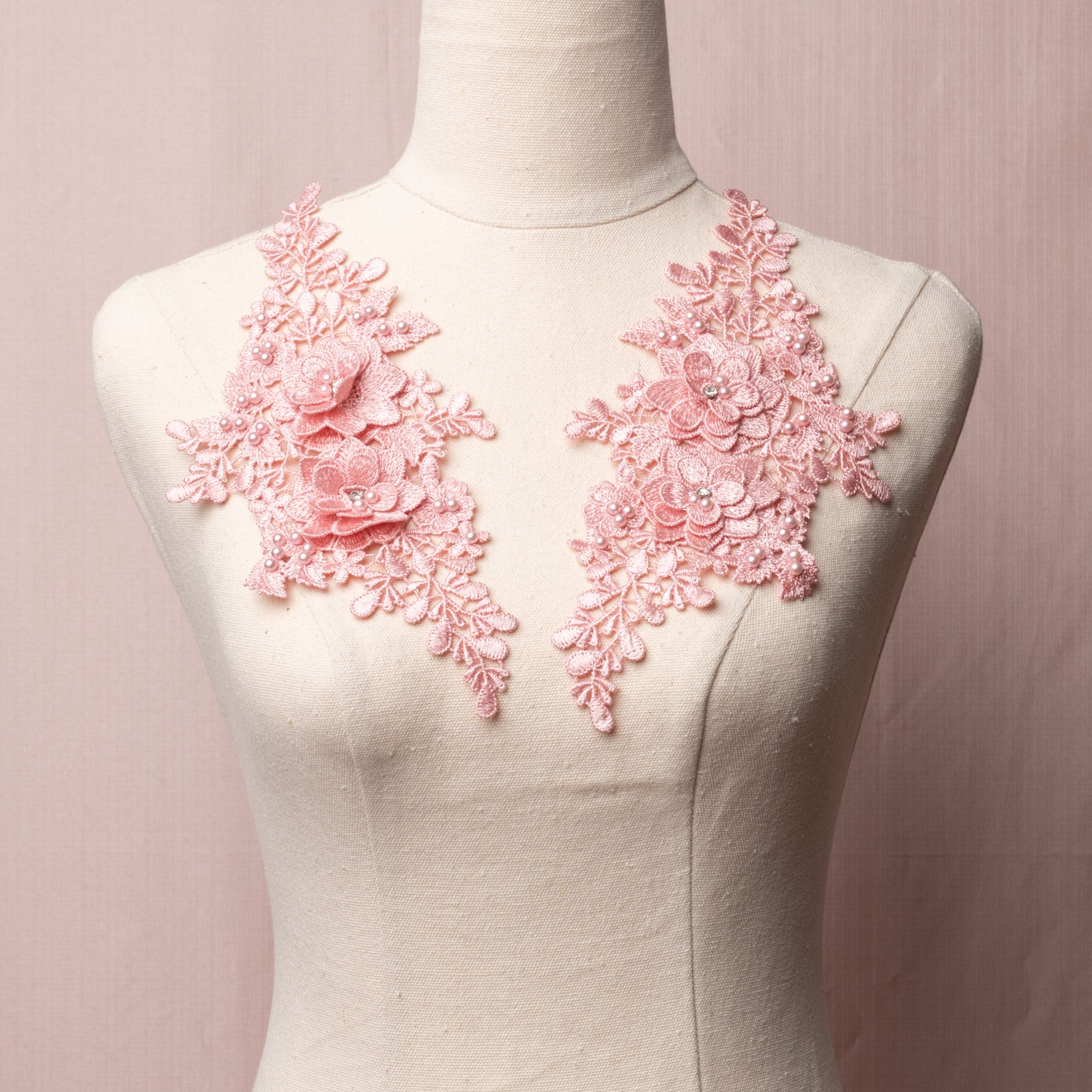 Pink mirrored pair embroidered applique with 3D flowers.  The applique is embellished with a scattering of pink pearls and the 3D flowers have a crystal centre and are displayed on a mannequin.