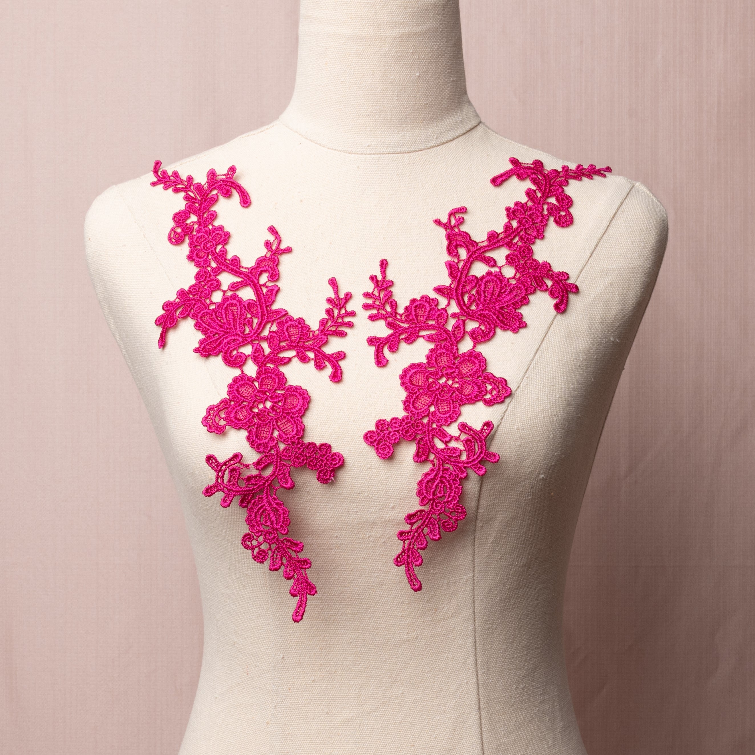 A deep rose coloured embroidered applique pair  displayed on a mannequin.