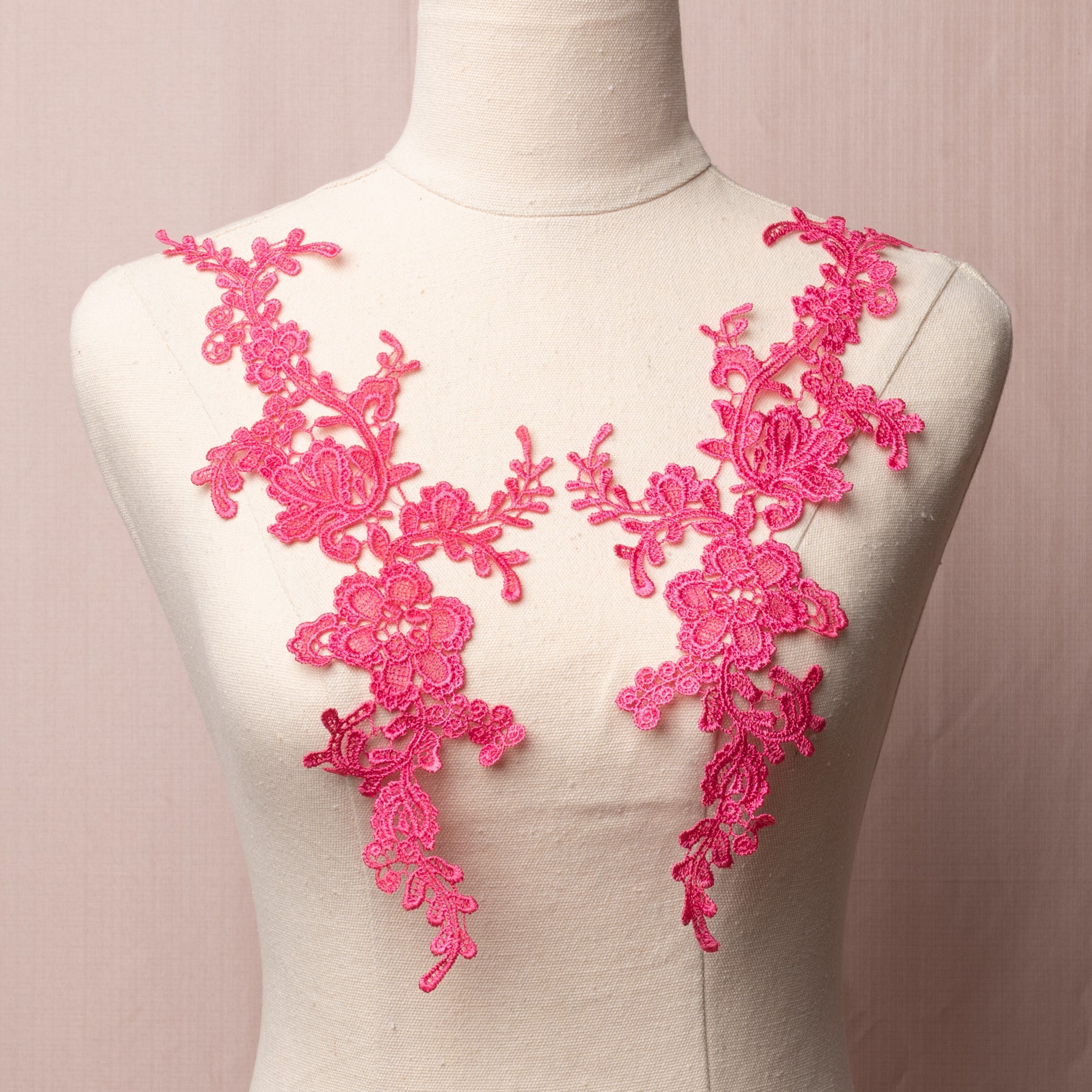 Heavily embroidered fuchsia floral applique pair displayed on a mannequin.