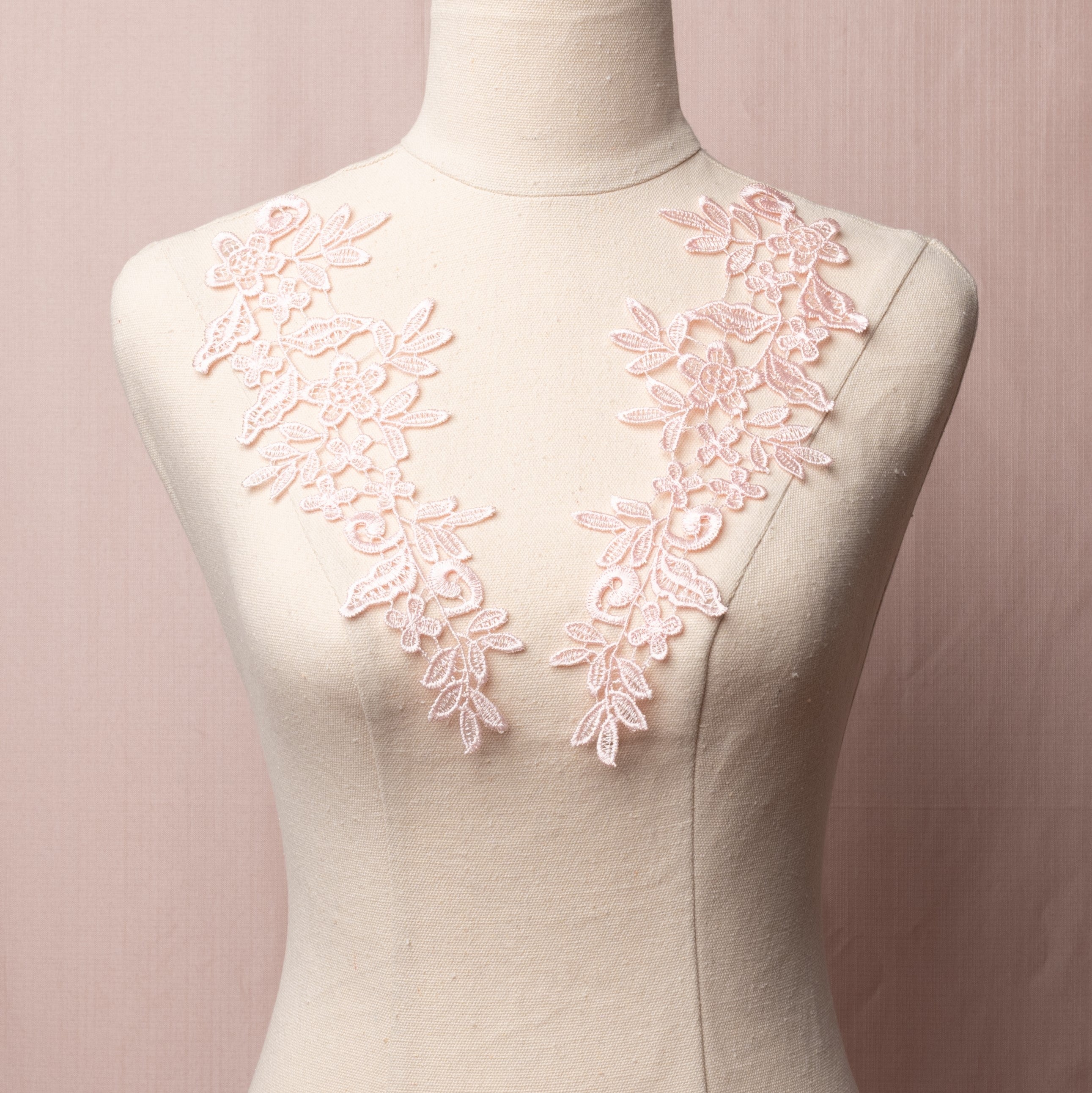 Heavily embroidered pale pink mirrored lace applique pair displayed on a mannequin.