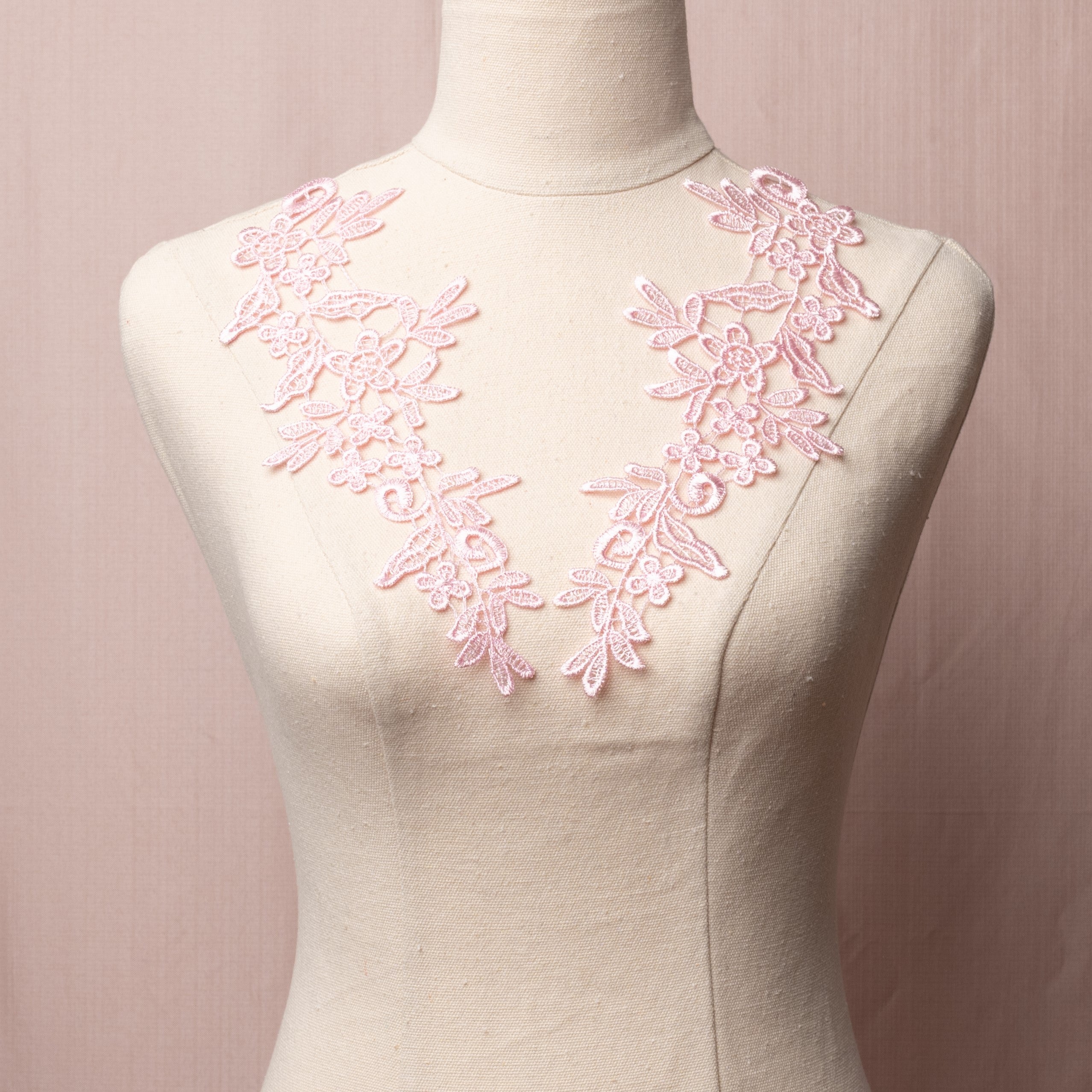 Heavily embroidered sugar pink mirrored lace applique pair displayed on a mannequin.