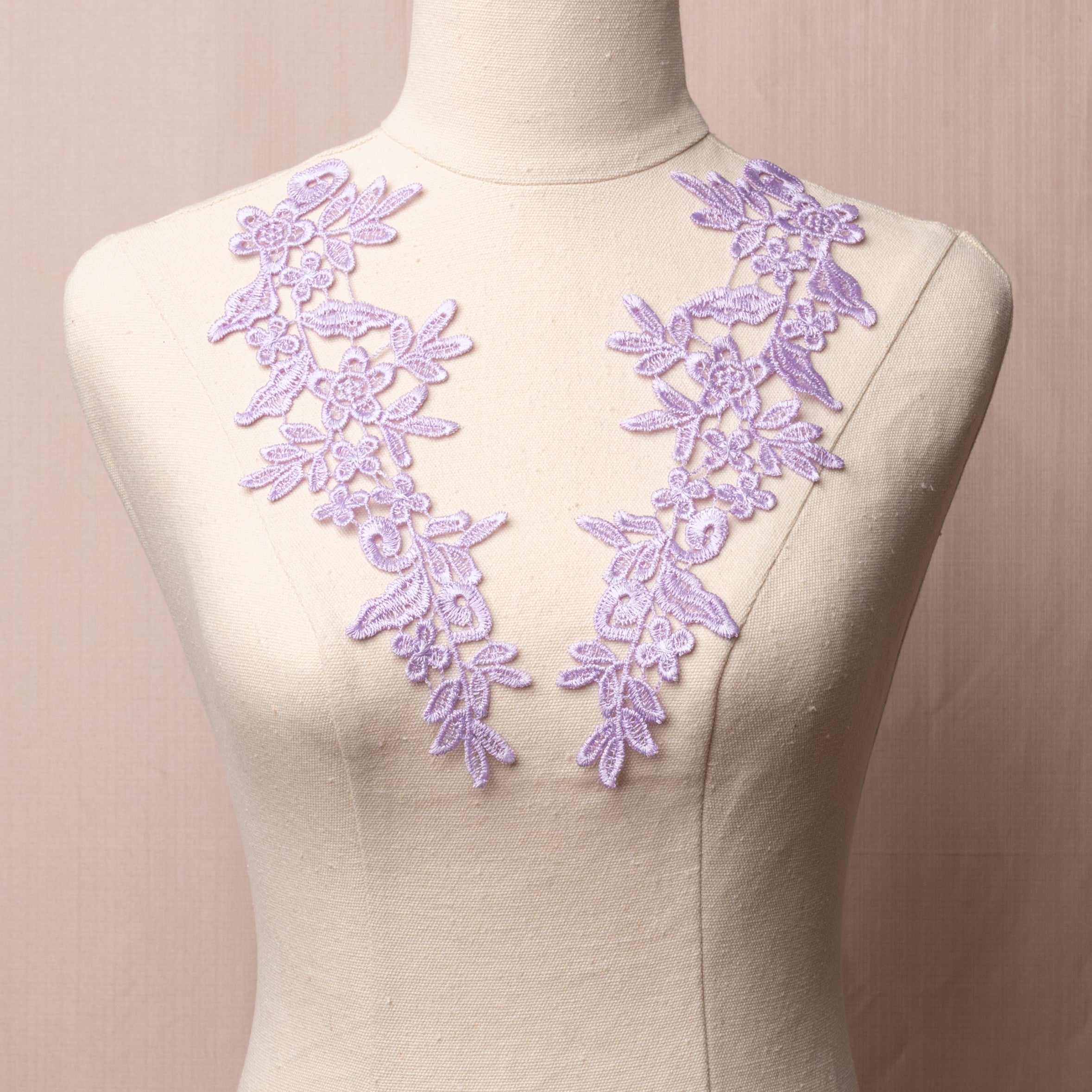 Heavily embroidered lilac lace applique pair with a floral design displayed on a mannequin.