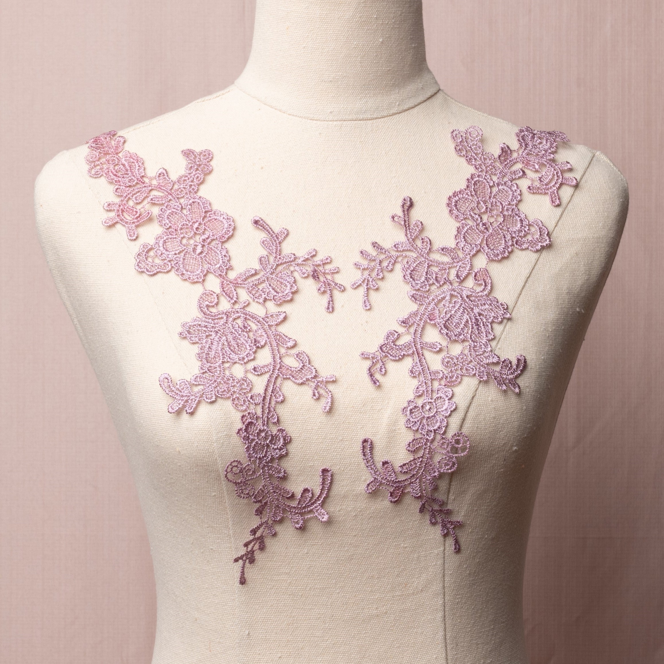 Heavily embroidered mauve floral applique pair displayed on a mannequin.