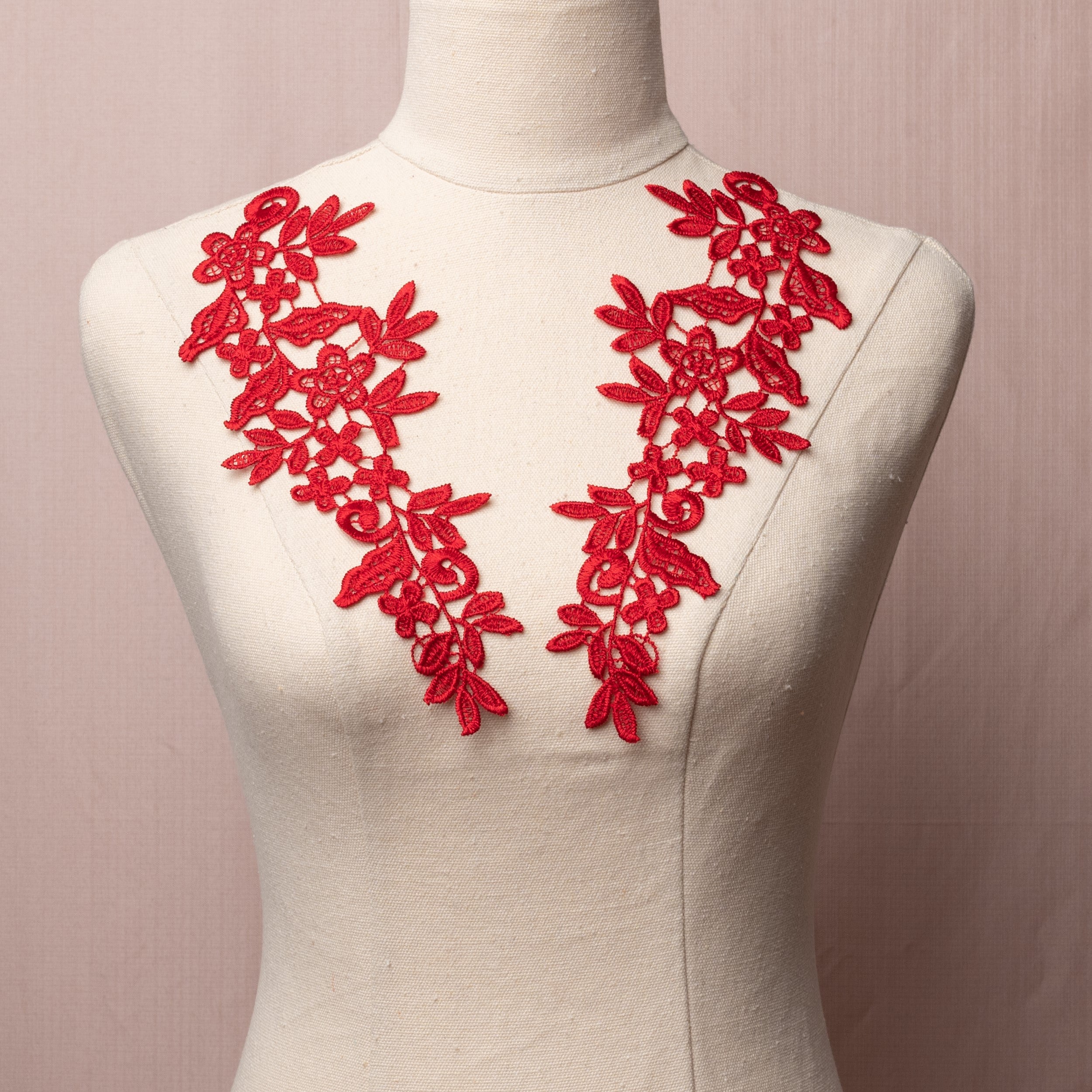 Red embroidered lace applique pair displayed on a mannequin.