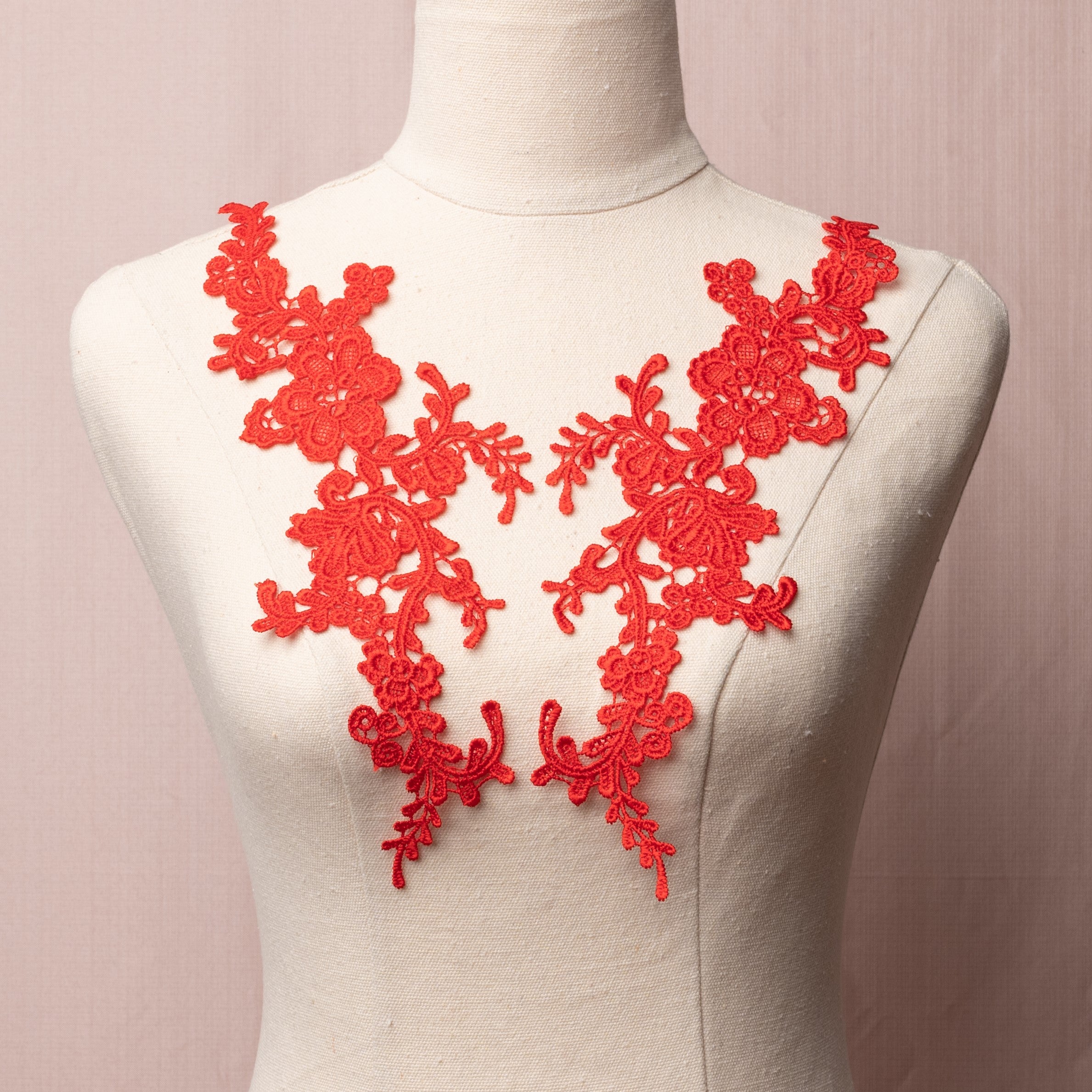 Heavily embroidered red floral applique pair displayed on a mannequin.
