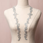 A narrow silver applique pair in a trailing leaf and flower pattern displayed on a mannequin.