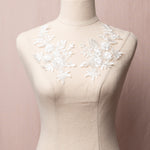 White embroidered 3D floral applique pair displayed on a mannequin.