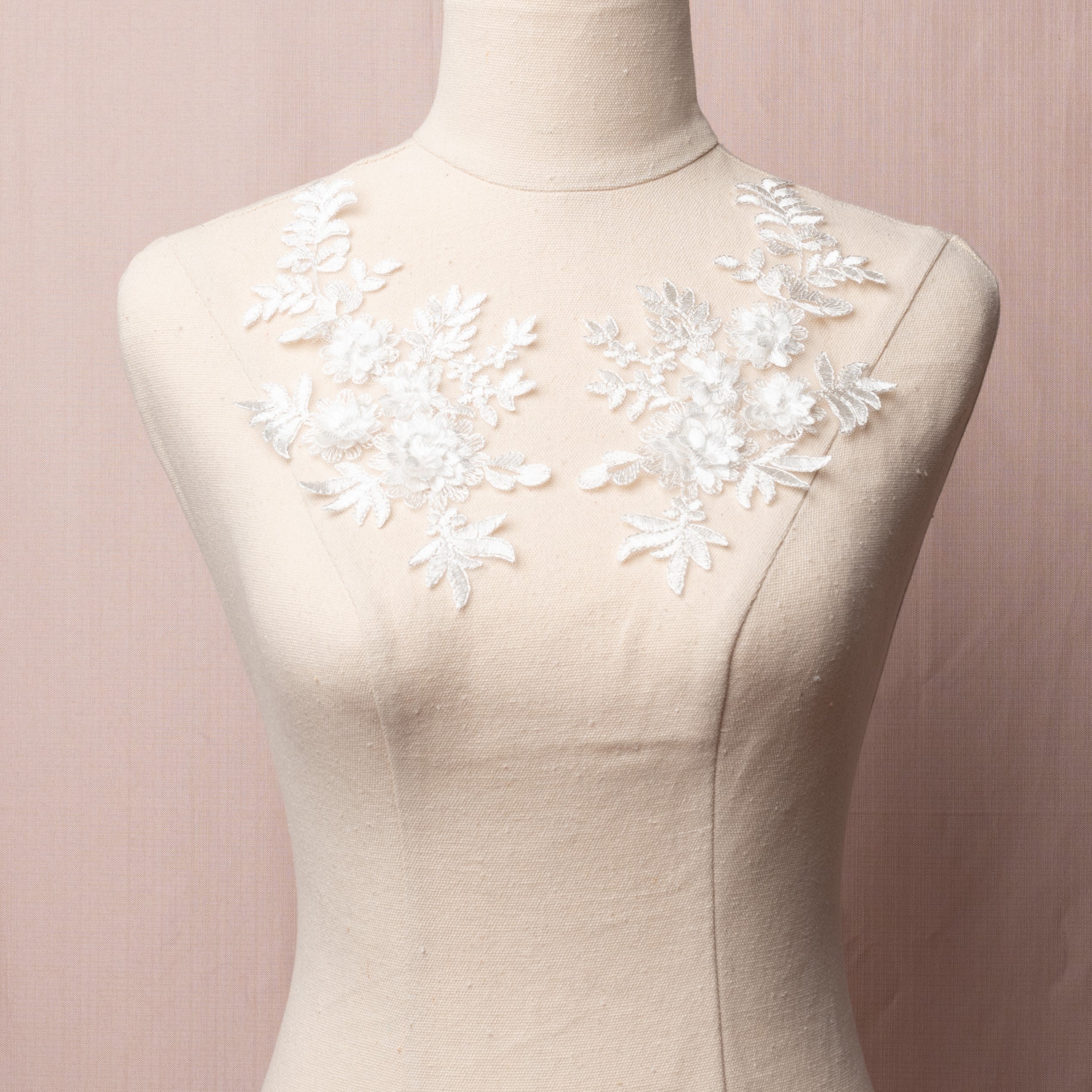 White embroidered 3D floral applique pair displayed on a mannequin.