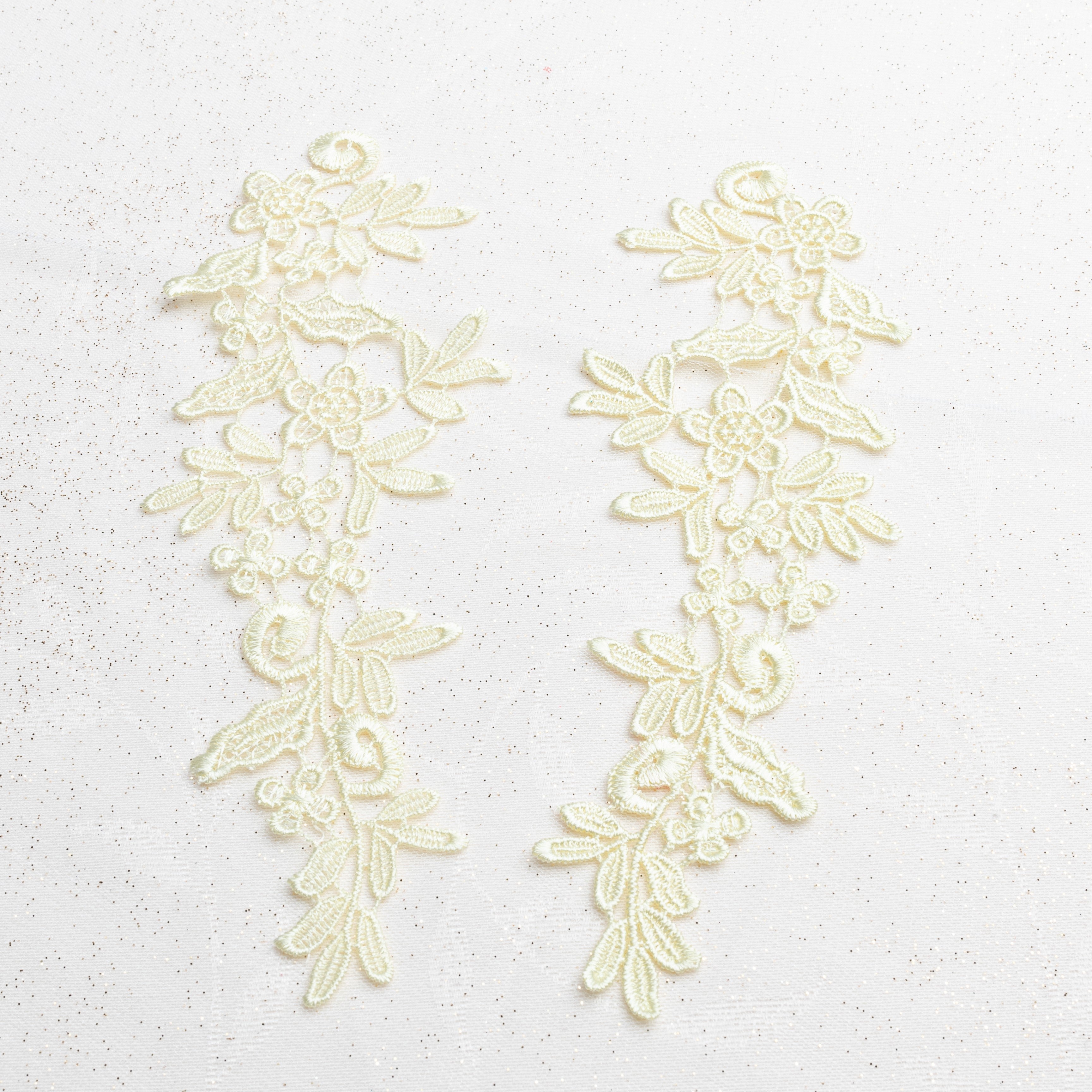 Heavily embroidered lemon yellow lace applique pair with a floral design laying flat on a white background.