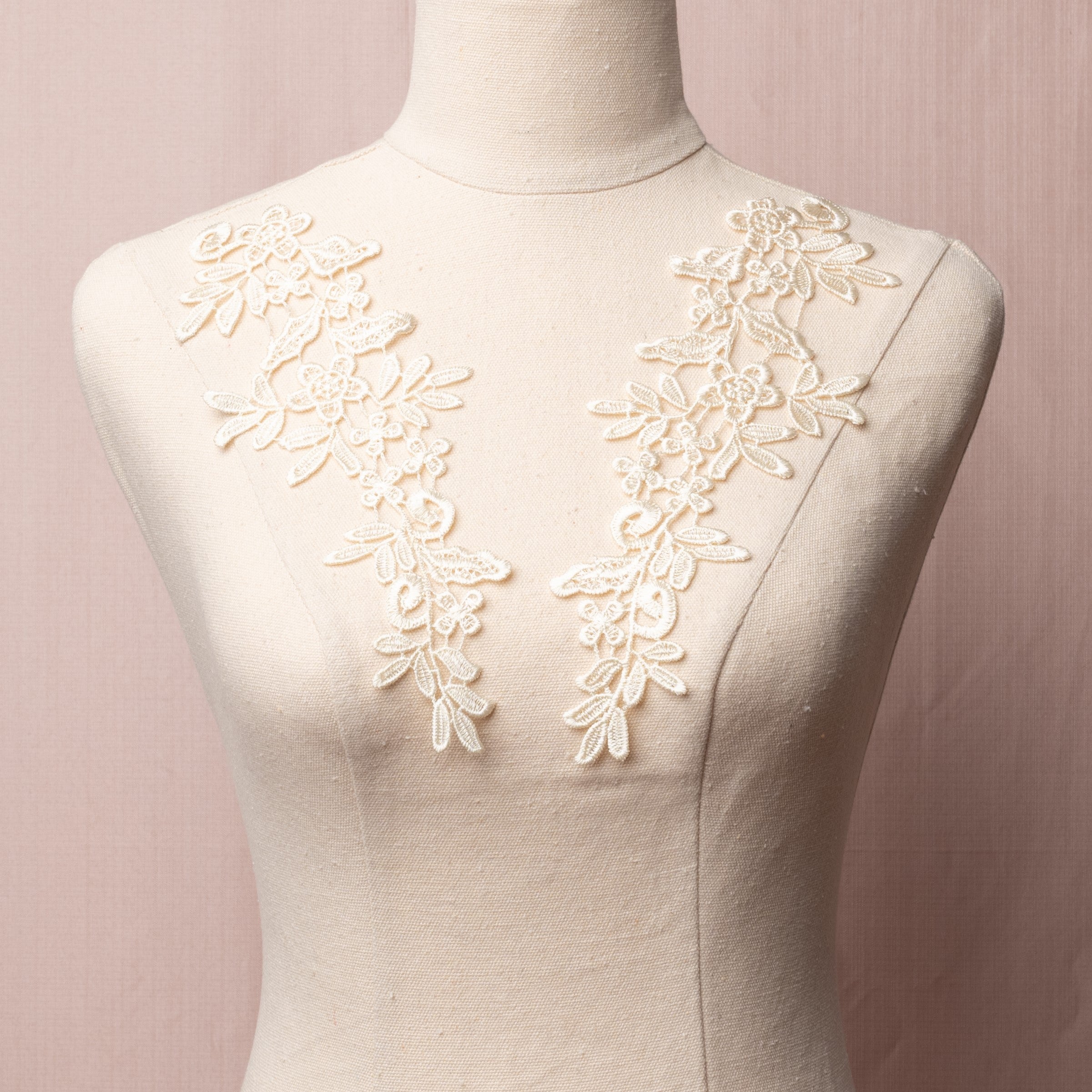 Heavily embroidered light cream yellow mirrored lace applique pair displayed on a mannequin.