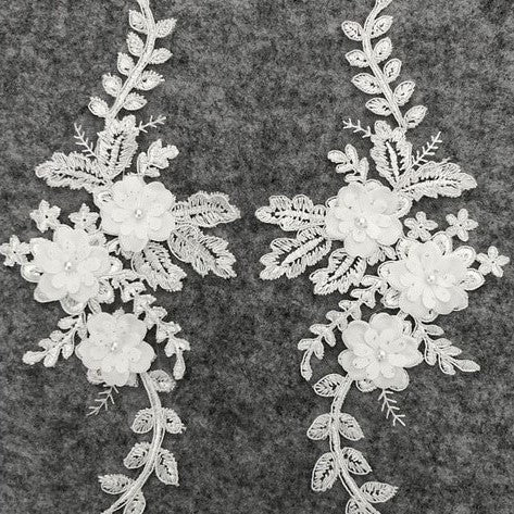 White 3D embroidered and corded appliques in a floral spray design.  The appliques are decorated with 3D floral flowers which have a white pearl centre.  