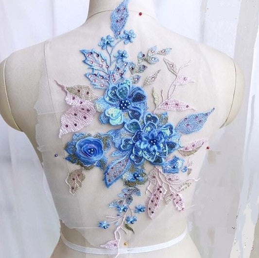A 3D applique with blue flowers and pink and gold leaves displayed as a costume decoration .
