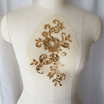 Bright gold fully sequined floral applique embroidered onto fine gold coloured net and displayed on a mannequin.