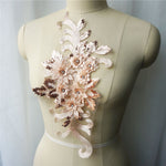 Single light apricot floral applique embroidered with metallic thread and embellished with sequinned leaves and 3D flowers that have a crystal centre.  The applique is displayed on a mannequin. 