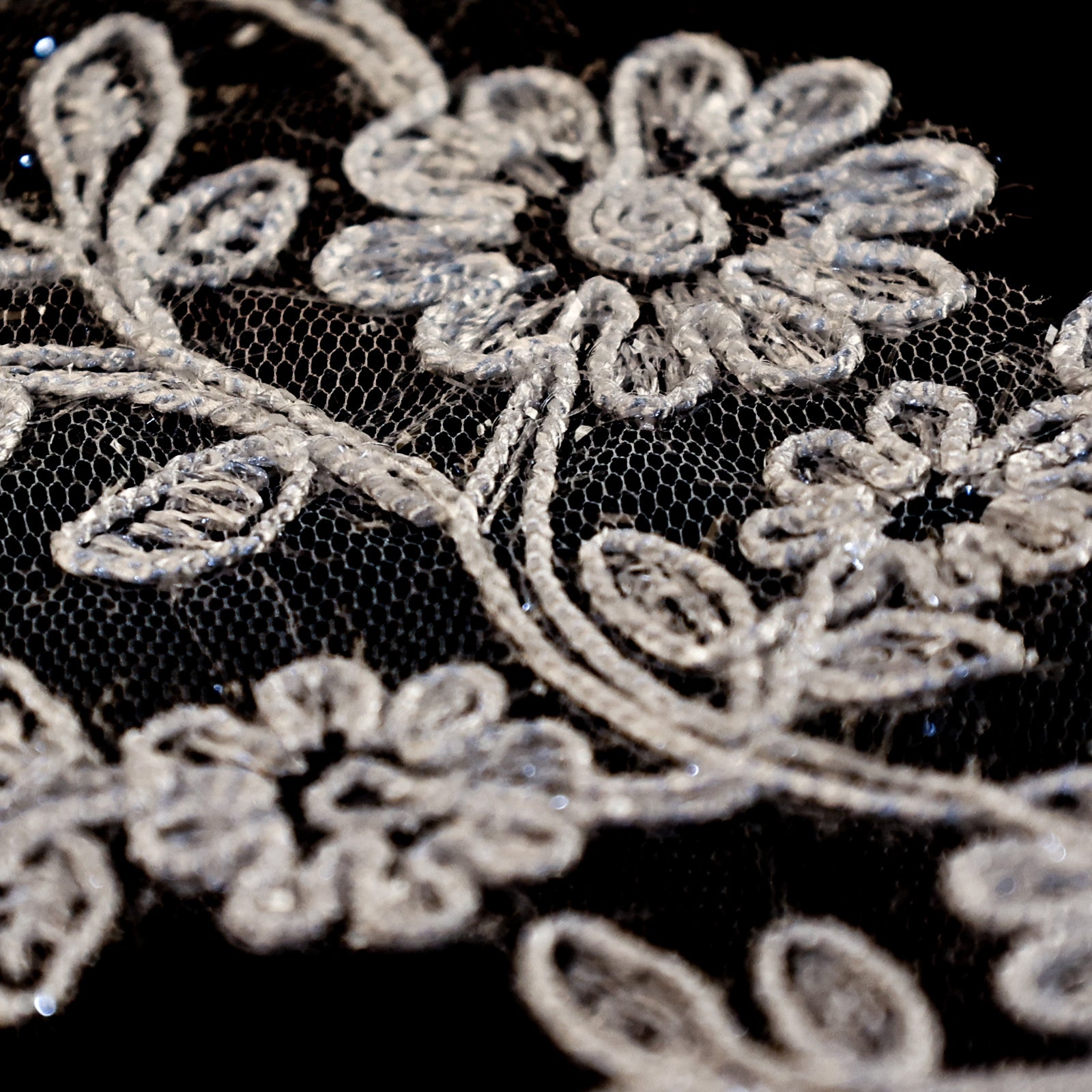 Close up of ivory floral applique embroidered with sparkly glitter thread.