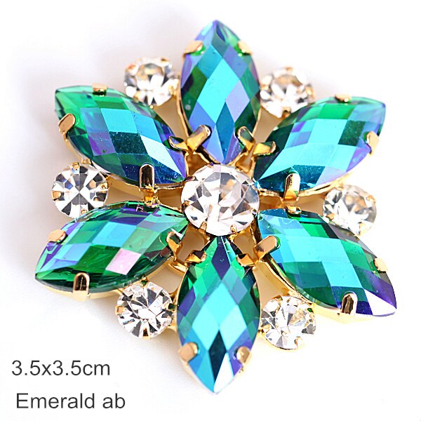 Flower shaped applique with tear drop shaped  emerald green petals and a crystal rhinestone centre.  There is a crystal rhinestone in between each petal. 
