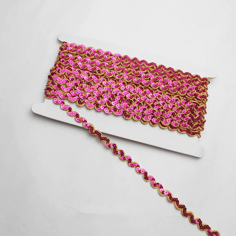 Fuchsia non-stretch sequins in a serpentine pattern edged with a metallic gold thread border.  the sequins are wrapped around a white card with a single strand lying flat across the image.