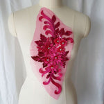 Single fuchsia floral applique embroidered with metallic thread and embellished with sequinned leaves and 3D flowers that have a crystal centre.  The applique is displayed on a mannequin. 
