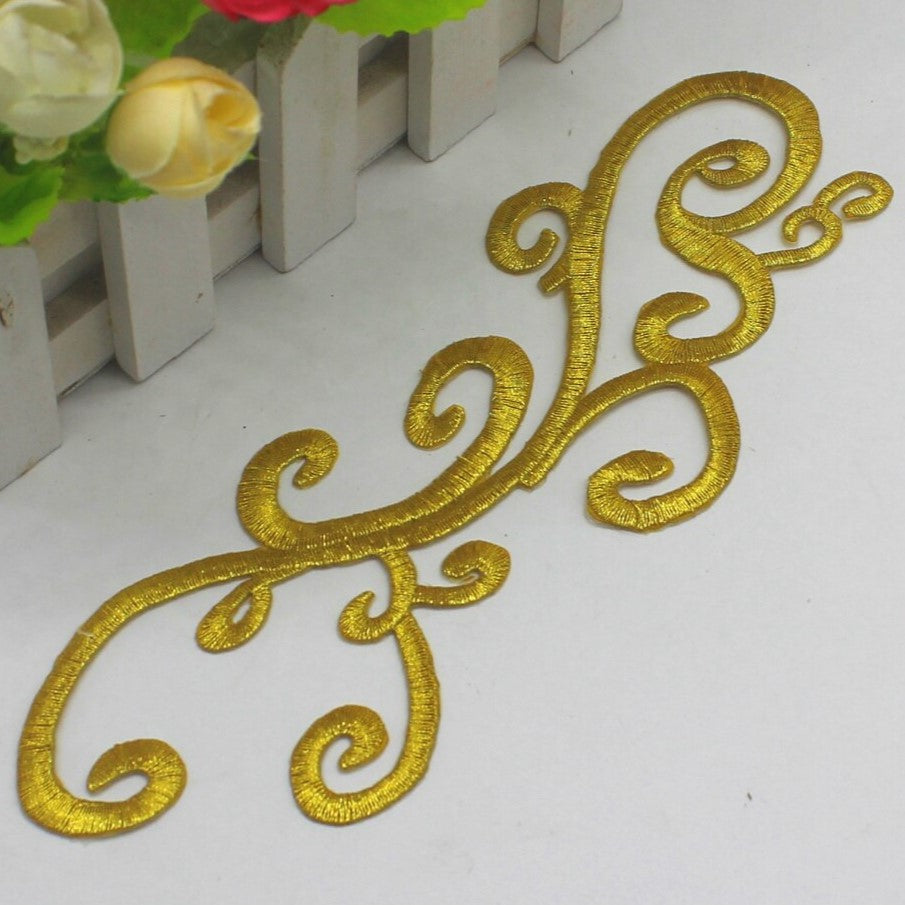 A gold embroidered iron on cosplay applique in a swirling design .