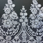 Stunning white lace with a floral pattern.  Each part of the design is outlined with silver thread and the flowers are embellished with silver sequins making the lace shimmer under lights.