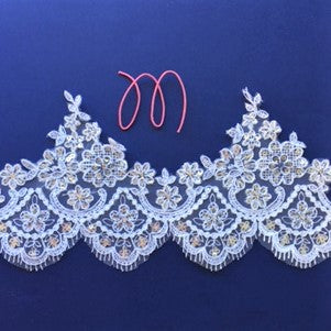 This border lace has a daisy design highlighted by a scalloped eyelash design on the lower edge . a firther scallop runs through the centre of the border . This gives the effect of a double scallop. Silver sequins heavily embellish the floral lace pattern.   