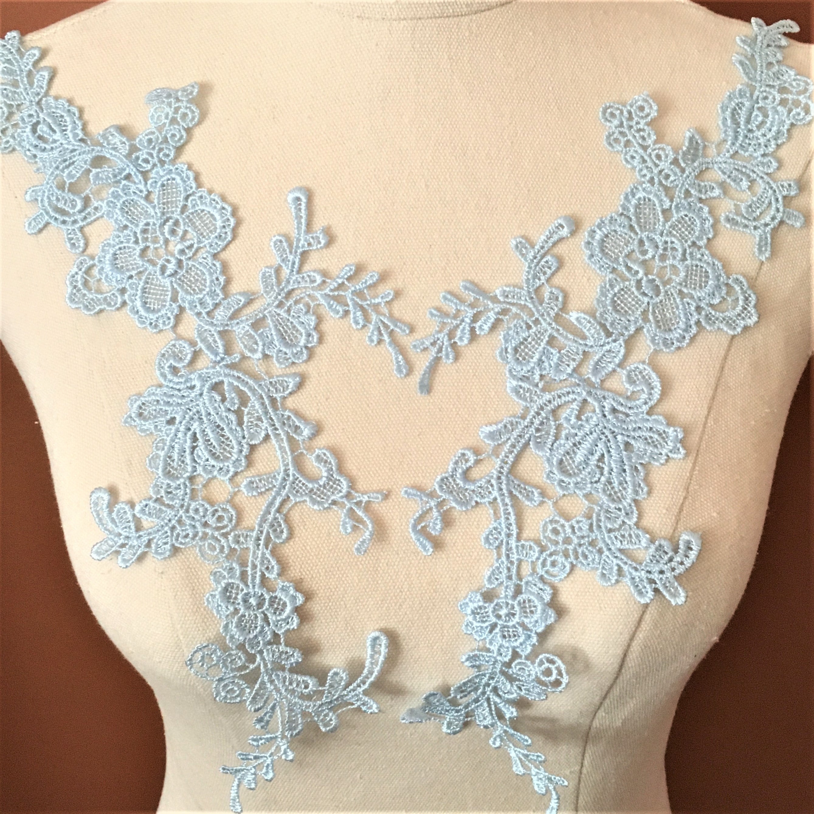 Finely embroidered pale blue applique pair. The applique is self embroidered without a backing net and is displayed on a mannequin.