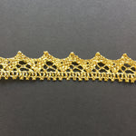 Metallic gold crocheted trim with a wave design laying flat on a black background.
