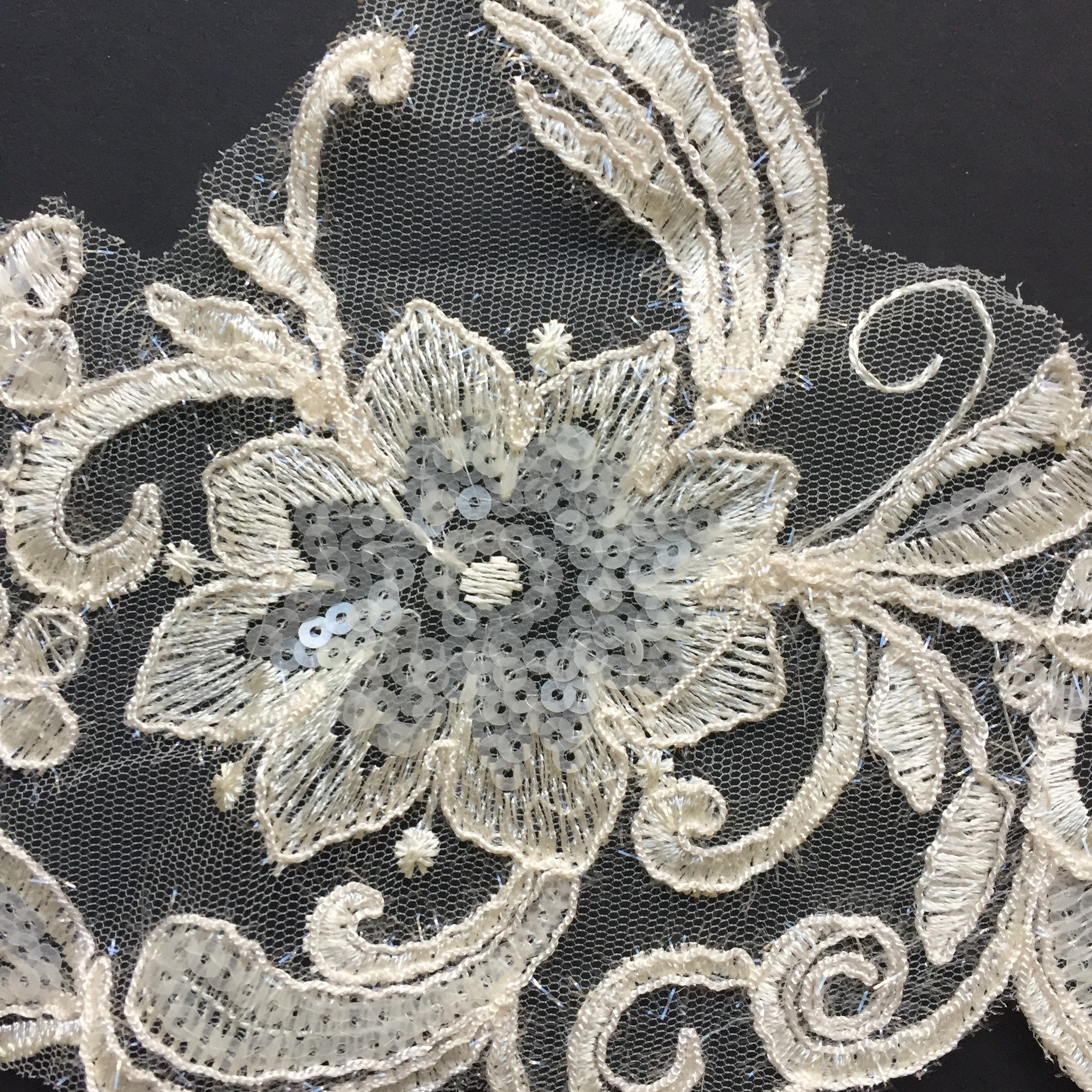 Small white opaque sequins fill the flower centres and leaf shapes.  Sparkly eyelash thread borders the outer edge of each motif.  