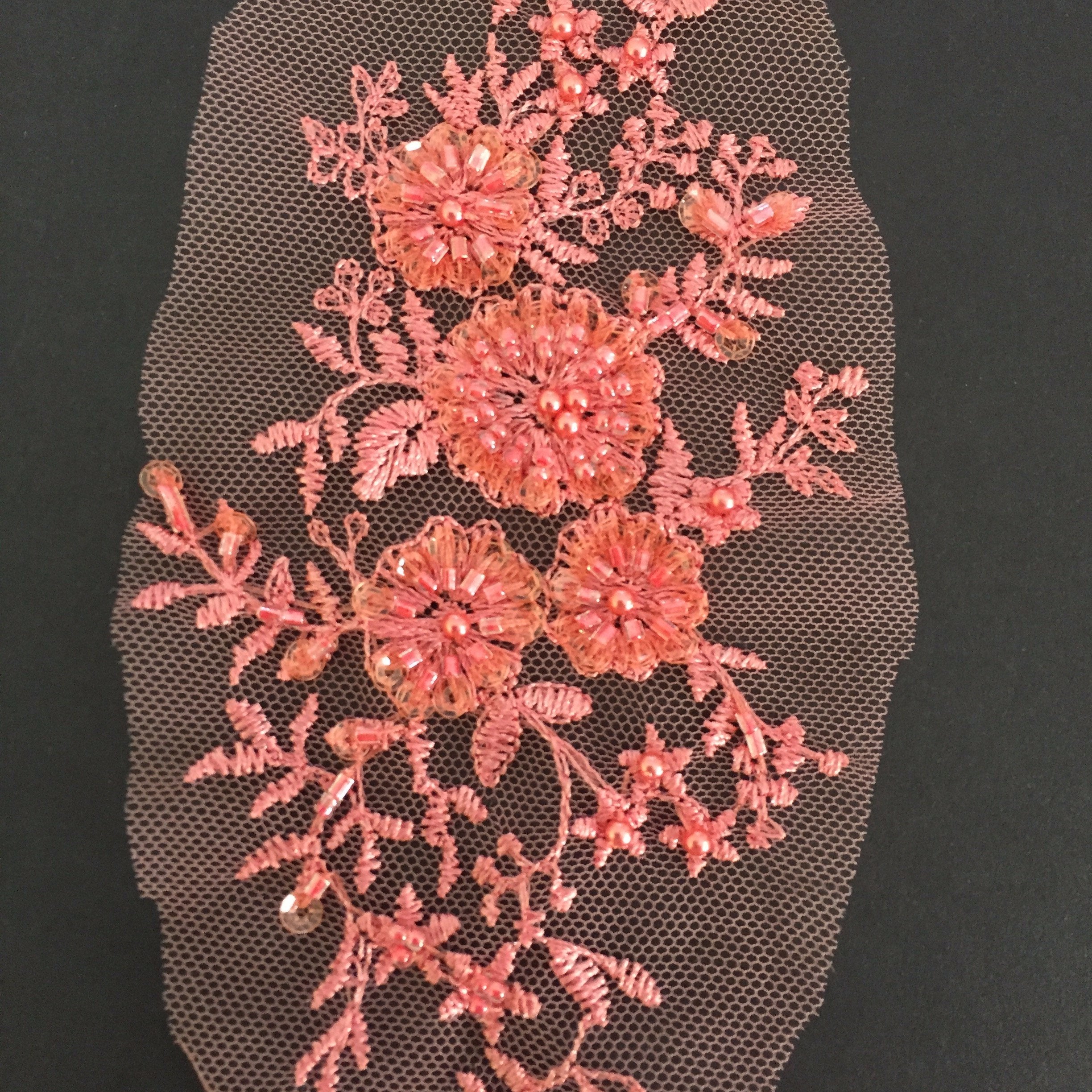 The central flowers are heavily beaded with tiny seed and bugle beads . Clear sequins are sewn at the tip of each petal  and a seed bead forms the flower centres