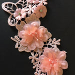 Close up of pink lace applique embellished with two large flowers.