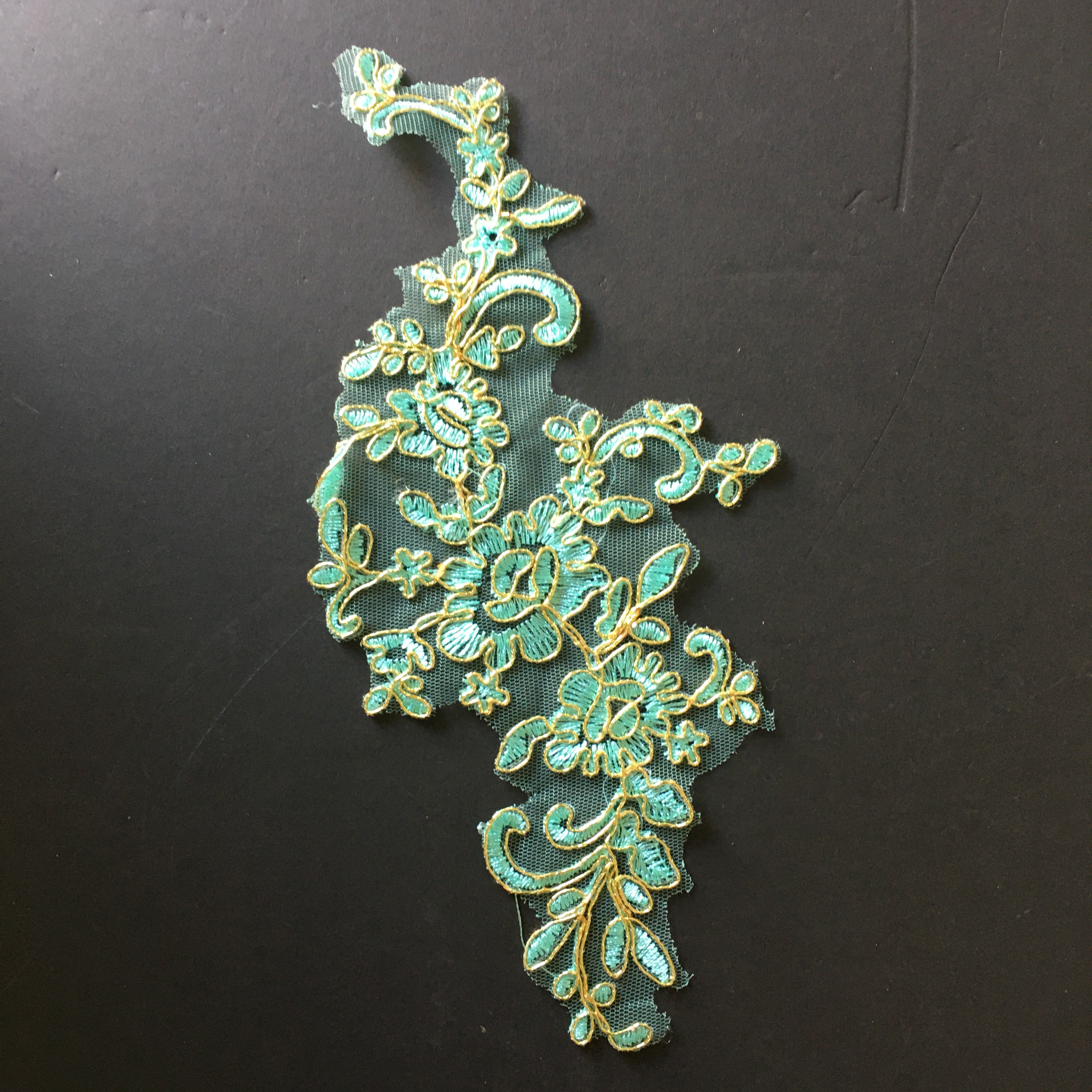 The floral pattern of leaves, stems and flowers is embroidered with aqua green thread onto a fine net backing.  Metallic gold cord outlines all motifs in the design. The embroidered design  is suitable for cutting and rearranging into a new applique design . o