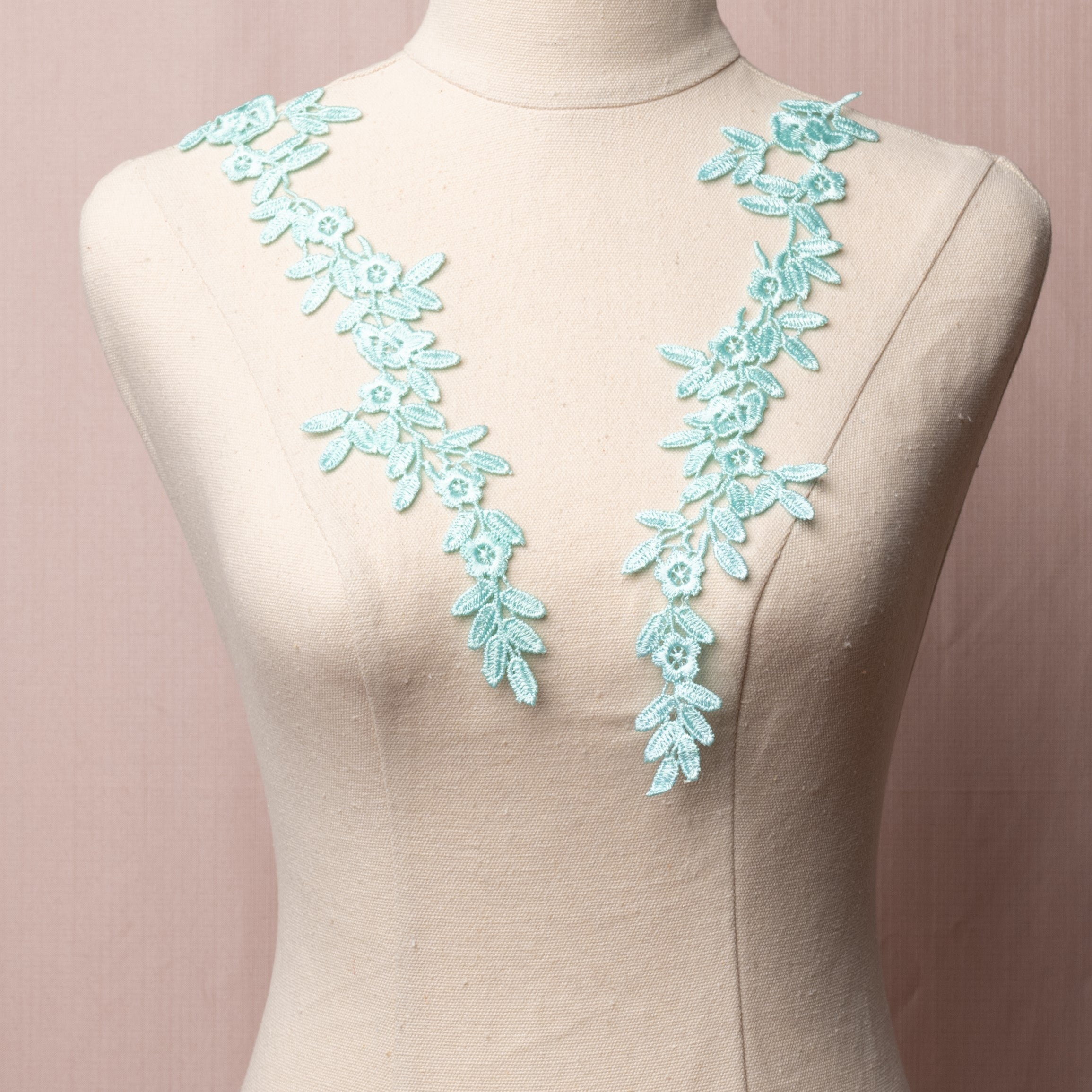 Long, narrow ice green embroidered applique pair with a floral design.  The appliques are displayed on a mannequin.