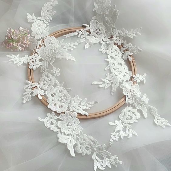A mirrored applique pair of off white appliques with an embroidered rose design .