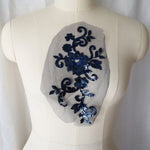 Navy blue fully sequined floral applique embroidered onto fine blue net and displayed on a mannequin.