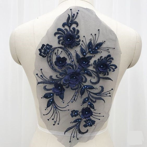 Navy blue floral 3D applique piece decorated with beads and embroidered onto a net backing.  The applique is displayed on a mannequin. 
