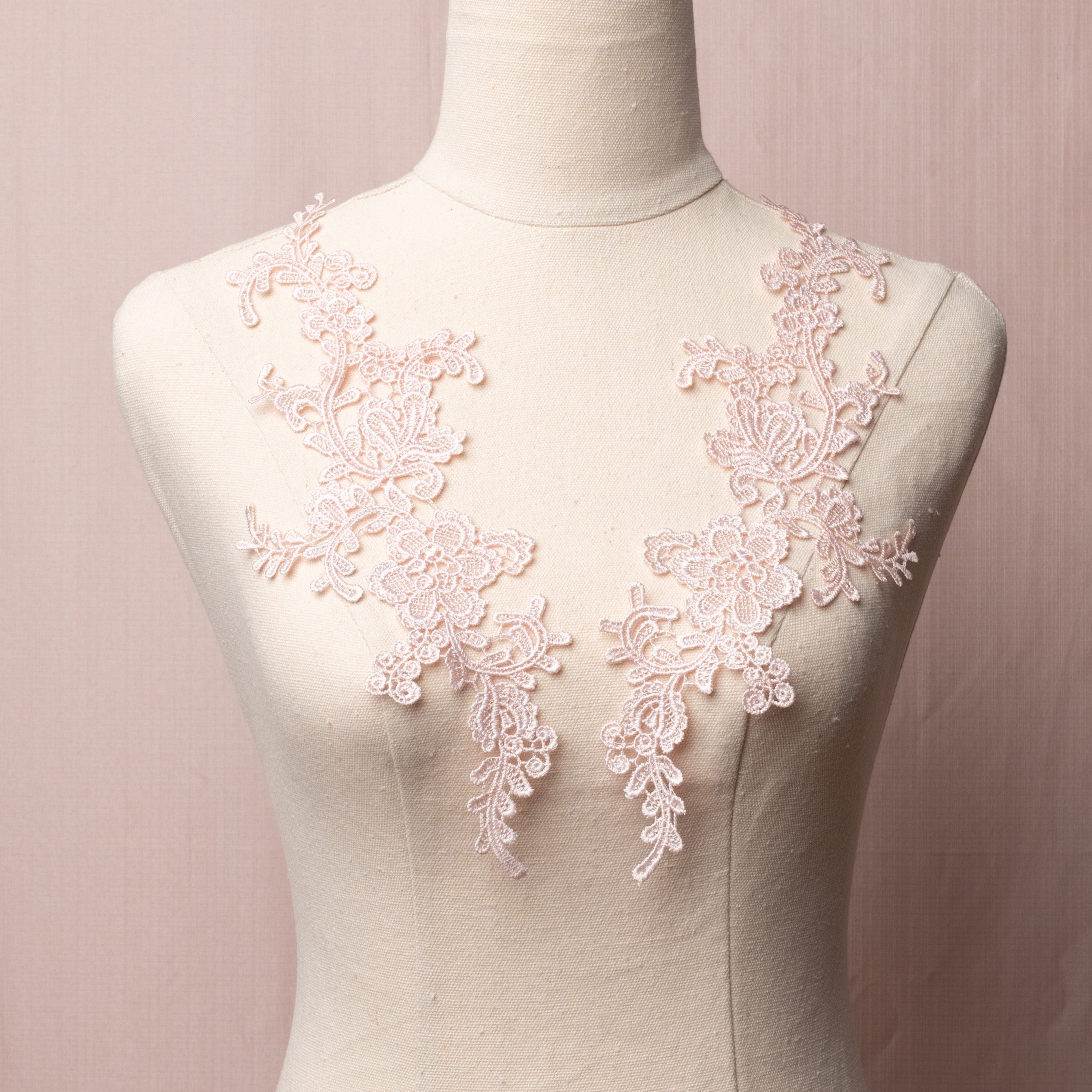 A light pink floral embroidered applique  displayed on a mannequin 