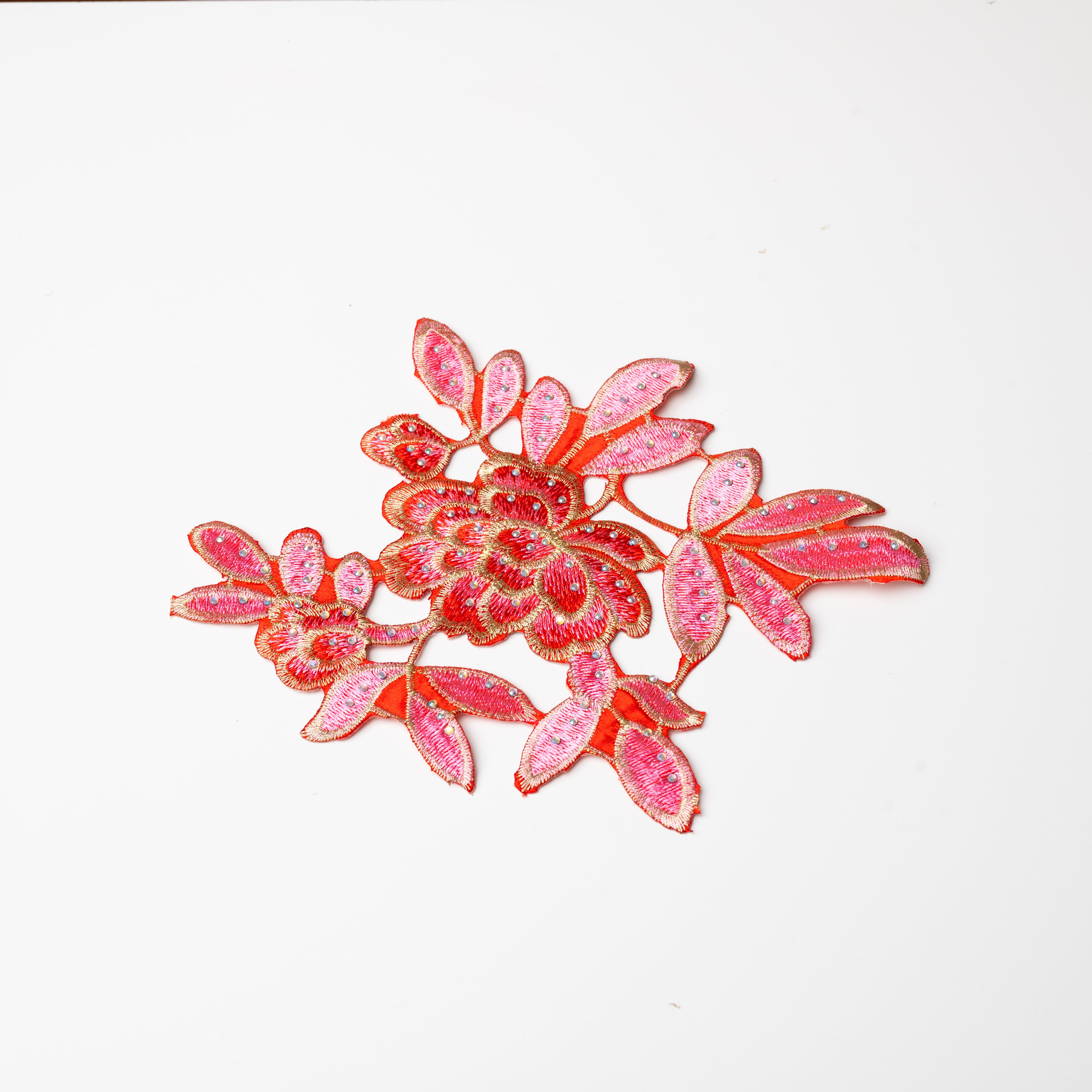 Heavily embroidered pink, red and gold floral iron on applique scattered with hot fix AB crystals.  The petals and leaves are predominantly pink and are outlined with gold thread.