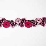 An embroidered trim with hot pink and pale pink flowers embroidered onto black velvet.  The trim is displayed on a white background.