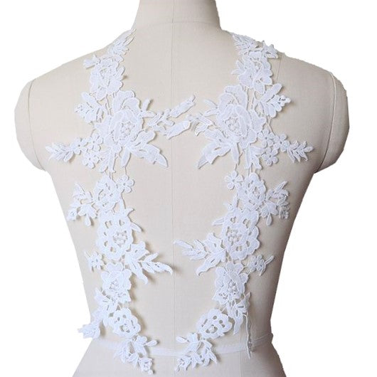 Long, trailing off white embroidered applique pair with a floral design.  The appliques are displayed on a mannequin. 