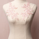 Pale pink embroidered and corded applique pair with a floral design and displayed on a mannequin.