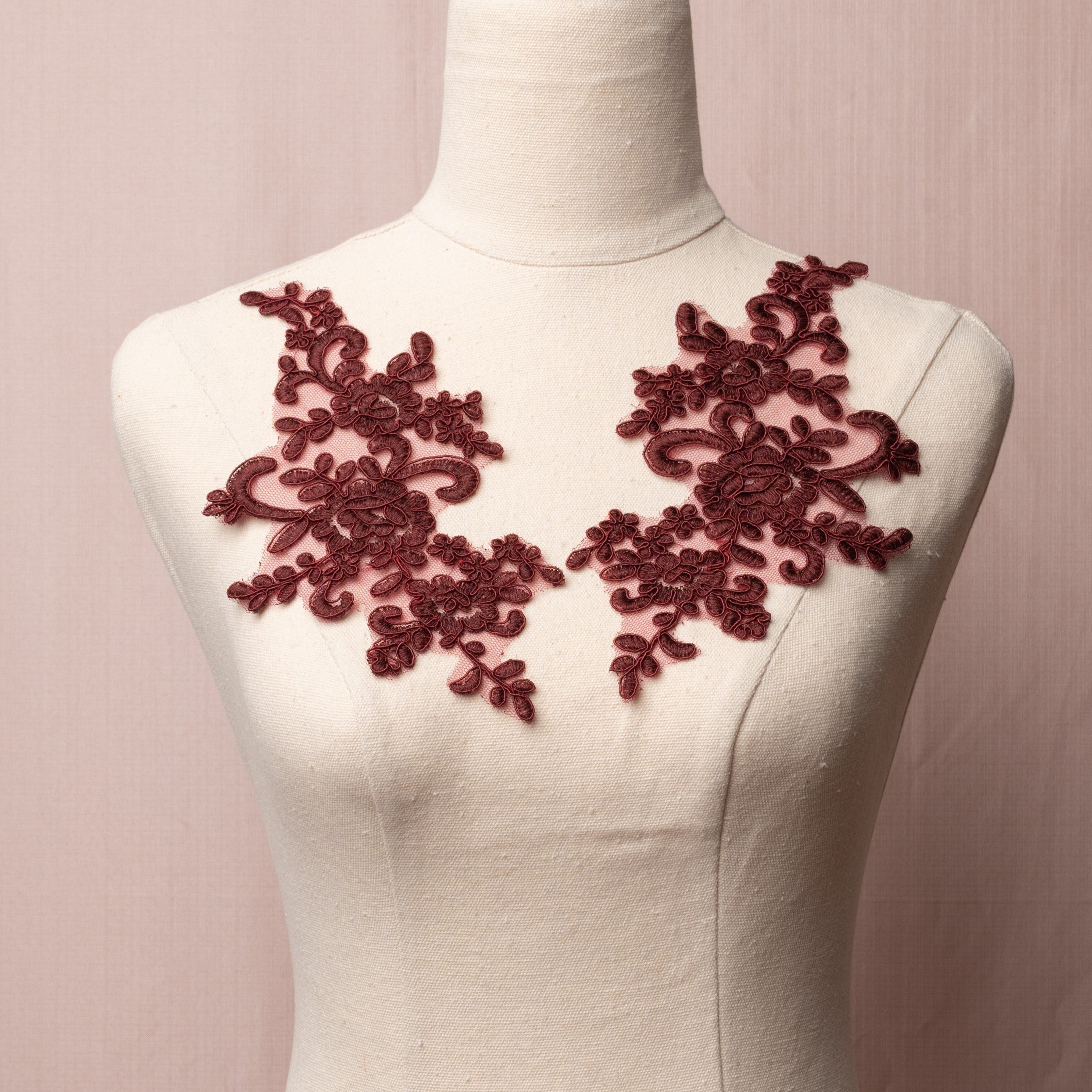 Mirrored pair of red brown corded floral appliques embroidered onto a fine net and displayed on a mannequin.