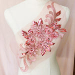 Single dusty pink floral applique embroidered with metallic thread and embellished with sequinned leaves and 3D flowers that have a crystal centre.  The applique is displayed on a mannequin. 