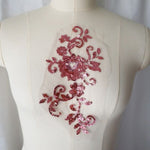 Salmon pink sequined floral applique embroidered onto fine white net and displayed on a mannequin.