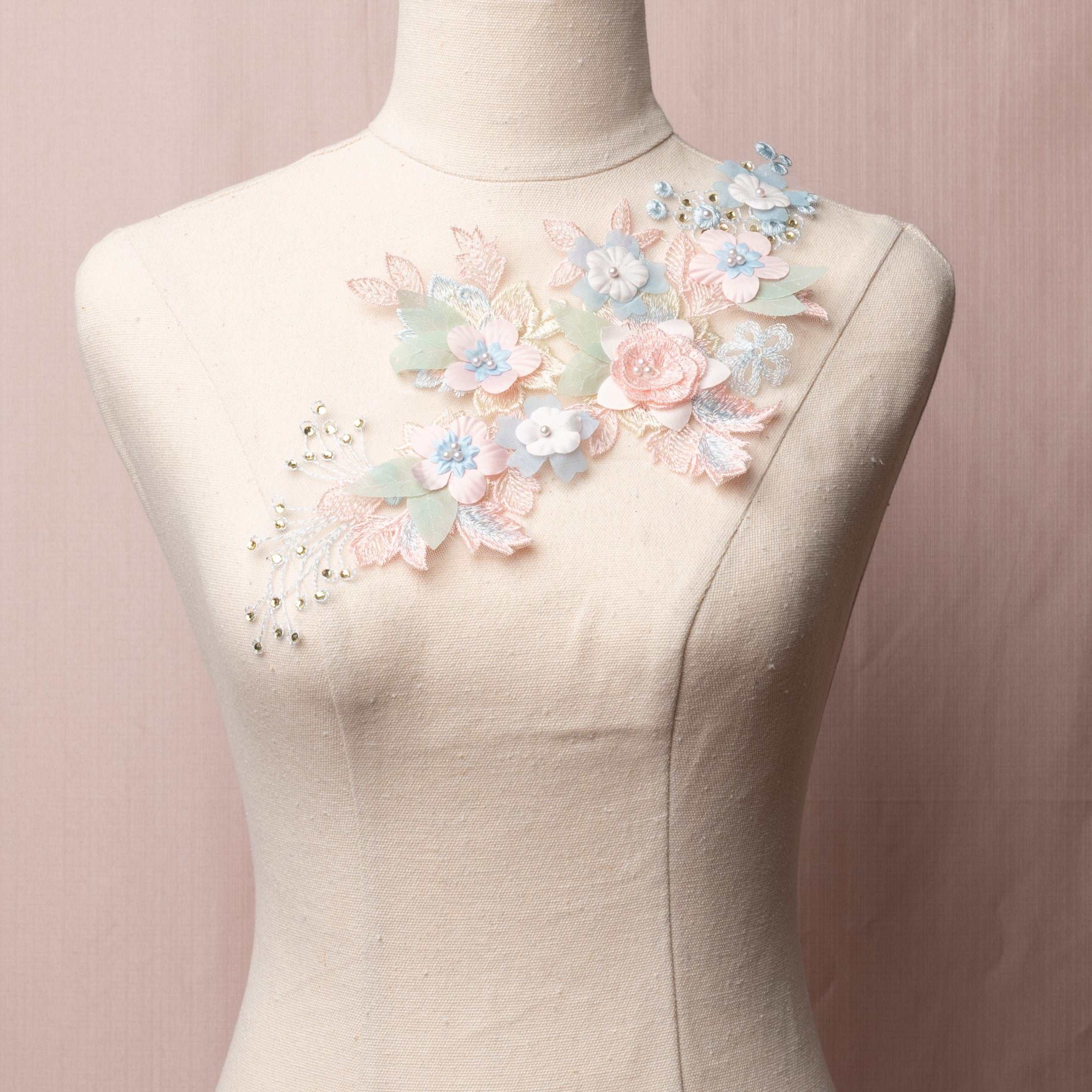 Single embroidered applique in pink , blue and sage green tones  embellished with 3D flowers and gems.  The applique is displayed on a mannequin.