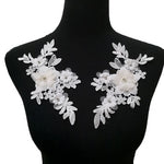 White embroidered applique pair embellished with 3D organza fabric flowers.  Flowers have a pearl and rhinestone centre.  The appliques are displayed on a mannequin.