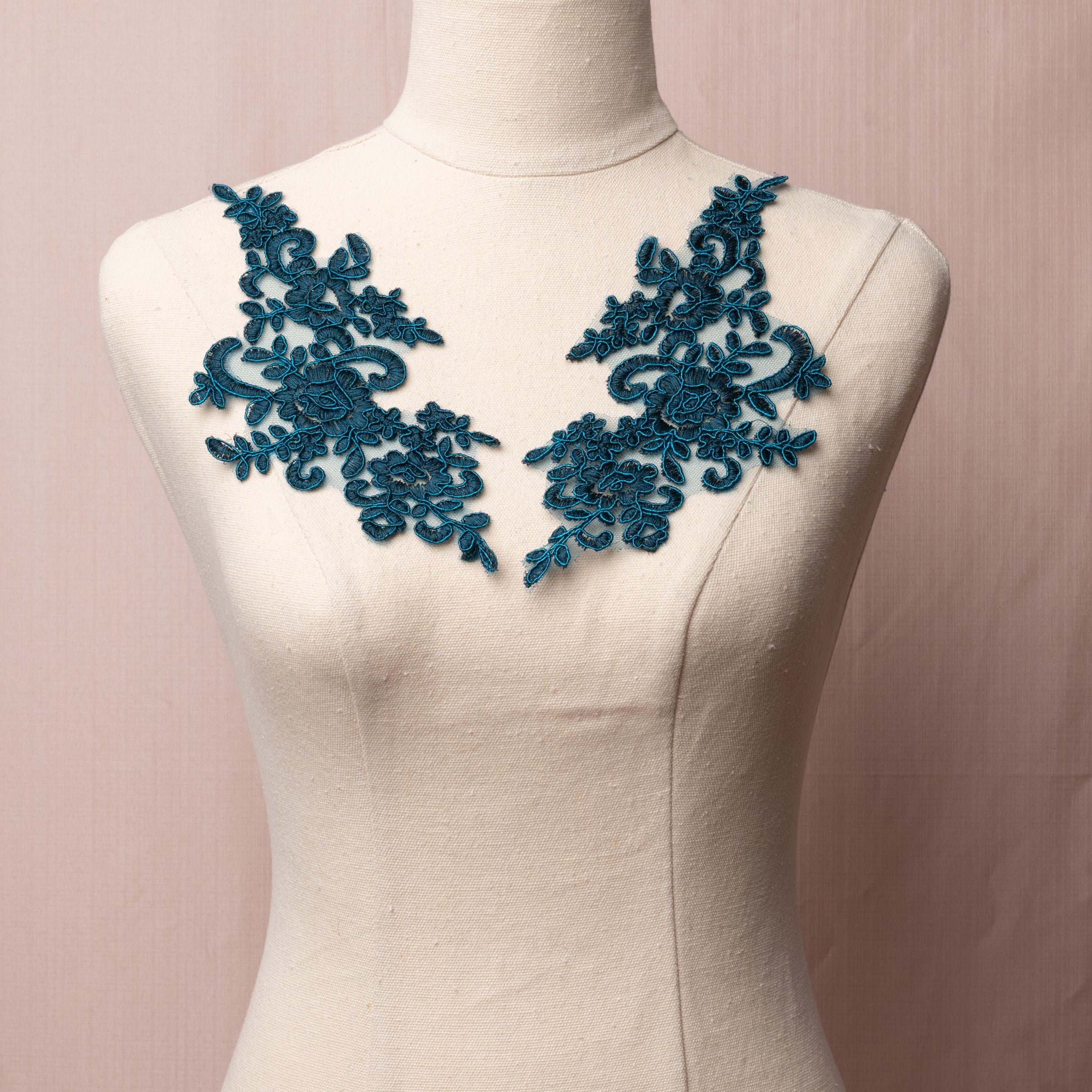 Mirrored pair of  teal peacock blue corded floral appliques embroidered onto a fine net and displayed on a mannequin