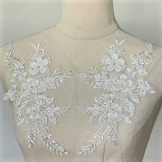 Heavily beaded white floral applique pair embroidered onto a net backing.  The appliques are decorated with 3D fabric flowers that have a beaded centre.  The appliques are displayed on a mannequin.