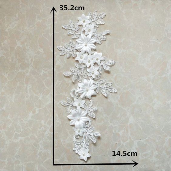 Single white corded floral applique embroidered onto an organza backing.  The applique is embellished with 3D fabric flowers that have a pearl centre.  The applique is laying flat on a pale coffee colored background that has a marble pattern effect.  The measurements of the applique are displayed.  The length is 35.2 cm and the width is 14.5 cm.